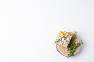 Christmas background with eco friendly packeged gift in craft paper and rosemary on white. Zero waste Christmas holiday concept. Flat lay, copy space photo