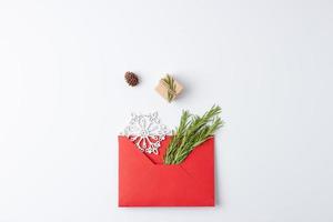 Minimal composition with red envelope, gift and Christmas natural decorations on white background. Flat lay, copy space photo