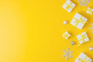 Christmas decorations with packaging gifts and balls on yellow background. Flat lay, copy space photo