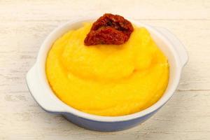 Polenta in a bowl on wooden background photo