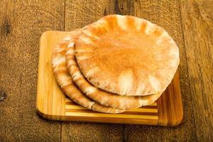 Pita bread on wooden board and wooden background photo