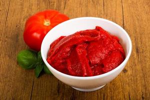 Tomato paste in a bowl on wooden background photo