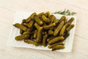 Picled cucumbers on the plate and wooden background photo