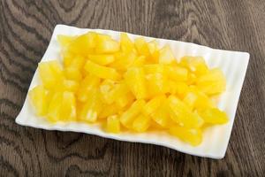 Canned pineapple on the plate and wooden background photo