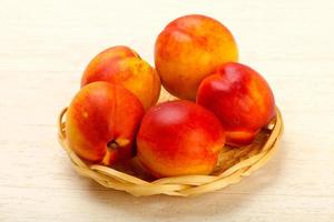 Nectarines in a basket on wooden background photo