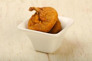 Dry figs in a bowl on wooden background photo