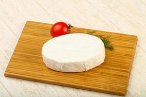 queso camembert sobre tabla de madera y fondo de madera foto