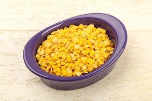 Yellow lentil in a bowl on wooden background photo