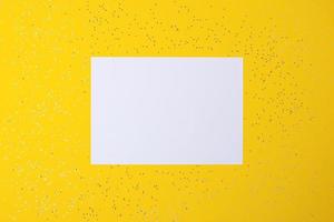 Christmas yellow minimal background with mock up greetings card and confetti. Flat lay, copy space photo