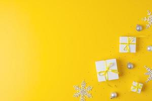 Christmas decorations with packaging gifts and balls on yellow background. Flat lay, copy space photo