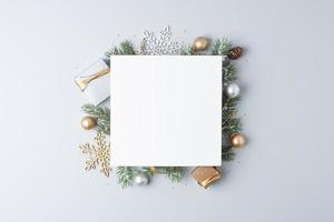 fondo mínimo de navidad con tarjeta de felicitación simulada y adornos navideños sobre fondo gris. endecha plana, espacio de copia foto