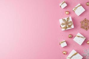 Christmas decorations with packaging gifts and balls on pink background. Flat lay, copy space photo