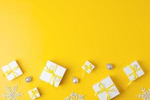 Christmas decorations with packaging gifts and balls on yellow background. Flat lay, copy space photo