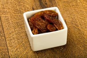 Dry Raisin in a bowl on wooden background photo