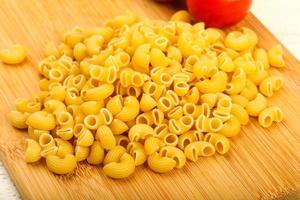 Raw pasta on wooden board and wooden background photo