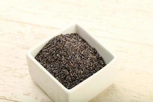 Poppy seeds in a bowl on wooden background photo