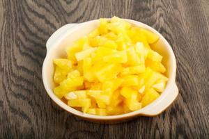 Canned pineapple in a bowl on wooden background photo