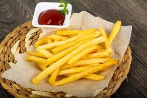 papas fritas en tablero de madera y fondo de madera foto