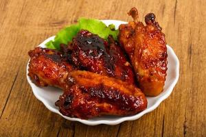 Chicken wings on the plate and wooden background photo