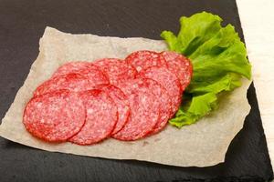 Salami sausage on wooden board and wooden background photo