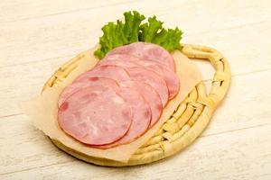 Sliced sausage on wooden board and wooden background photo