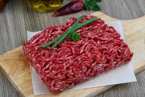 Minced beef on wooden board and wooden background photo