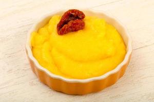 Polenta in a bowl on wooden background photo