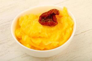 Polenta in a bowl on wooden background photo