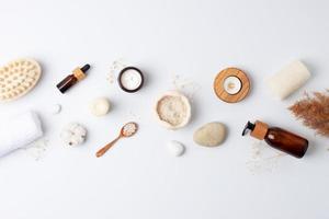 Spa treatment with natural skin care products flowers, towel and wash on white background. Flat lay, copy space. photo