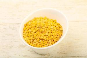 Yellow lentil in a bowl on wooden background photo
