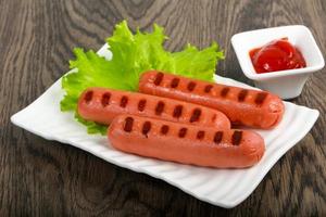 Grilled sausages on the plate and wooden background photo