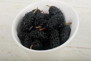 Black Mulberry in a bowl on wooden background photo