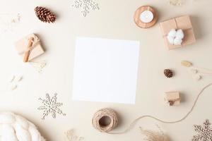 fondo de navidad con tarjeta de felicitación simulada y adornos navideños en beige pastel. endecha plana, espacio de copia foto