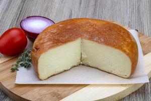 Suluguni cheese on wooden board and wooden background photo