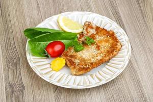 Pork schnitzel on the plate and wooden background photo