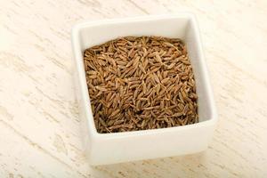 Cumin seeds in a bowl on wooden background photo