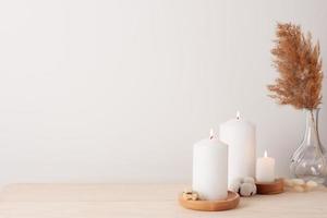 Home decoration with candles and flowers over white wall. Interior design concept. Close up, copy space photo