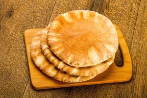 pan de pita sobre tablero de madera y fondo de madera foto