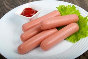 Sausages on the plate and wooden background photo