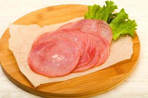 Sliced sausage on wooden board and wooden background photo