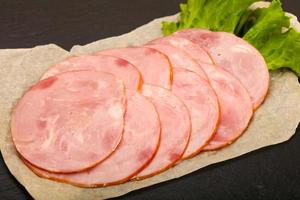 Sliced sausage on wooden board and wooden background photo