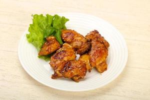 Teriyaki thighs on the plate and wooden background photo