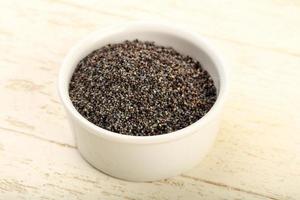 Poppy seeds in a bowl on wooden background photo