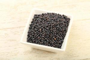 Black lentils in a bowl on wooden background photo