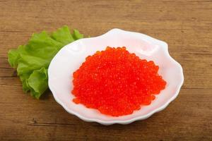 Red caviar on the plate and wooden background photo