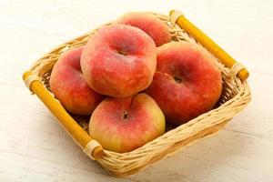 Sweet peaches in a basket on wooden background photo