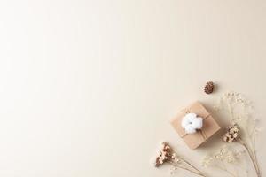 Christmas background with packaging gift in craft paper and flowers on beige. Flat lay, copy space photo