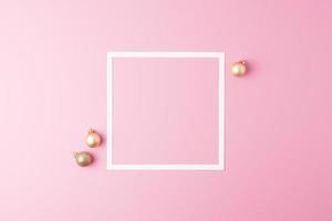 Christmas pink minimal background with white frame and beige ball. Flat lay, copy space photo