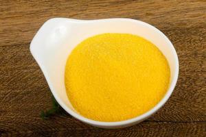 Raw polenta in a bowl on wooden background photo
