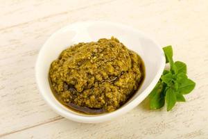 Pesto sauce in a bowl on wooden background photo